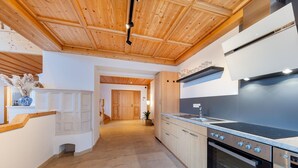 Una cocina moderna con techo de madera, armarios empotrados, una estufa negra y un horno de acero inoxidable.