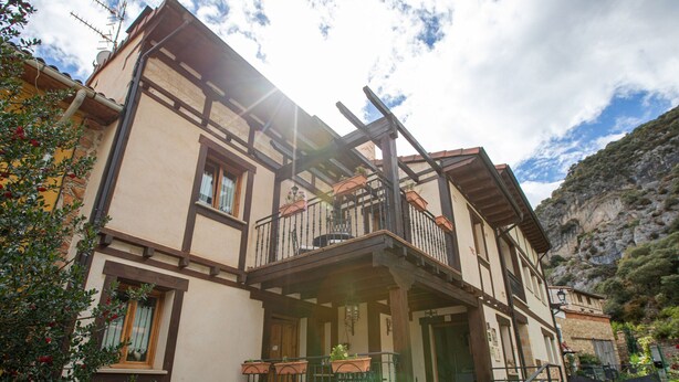 A traditional two-story building with a balcony, stone steps, and potted plants. - Chalet in Toba With Garden & Fireplace (Frias)