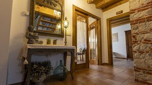 A hallway with a wooden floor, a stone wall, and a mirror above a console table with plants and a Buddha statue. - Chalet in Toba With Garden & Fireplace (Frias)