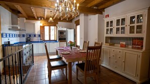 A spacious kitchen with wooden beams, a chandelier, and white cabinets. - Chalet in Toba With Garden & Fireplace (Frias)