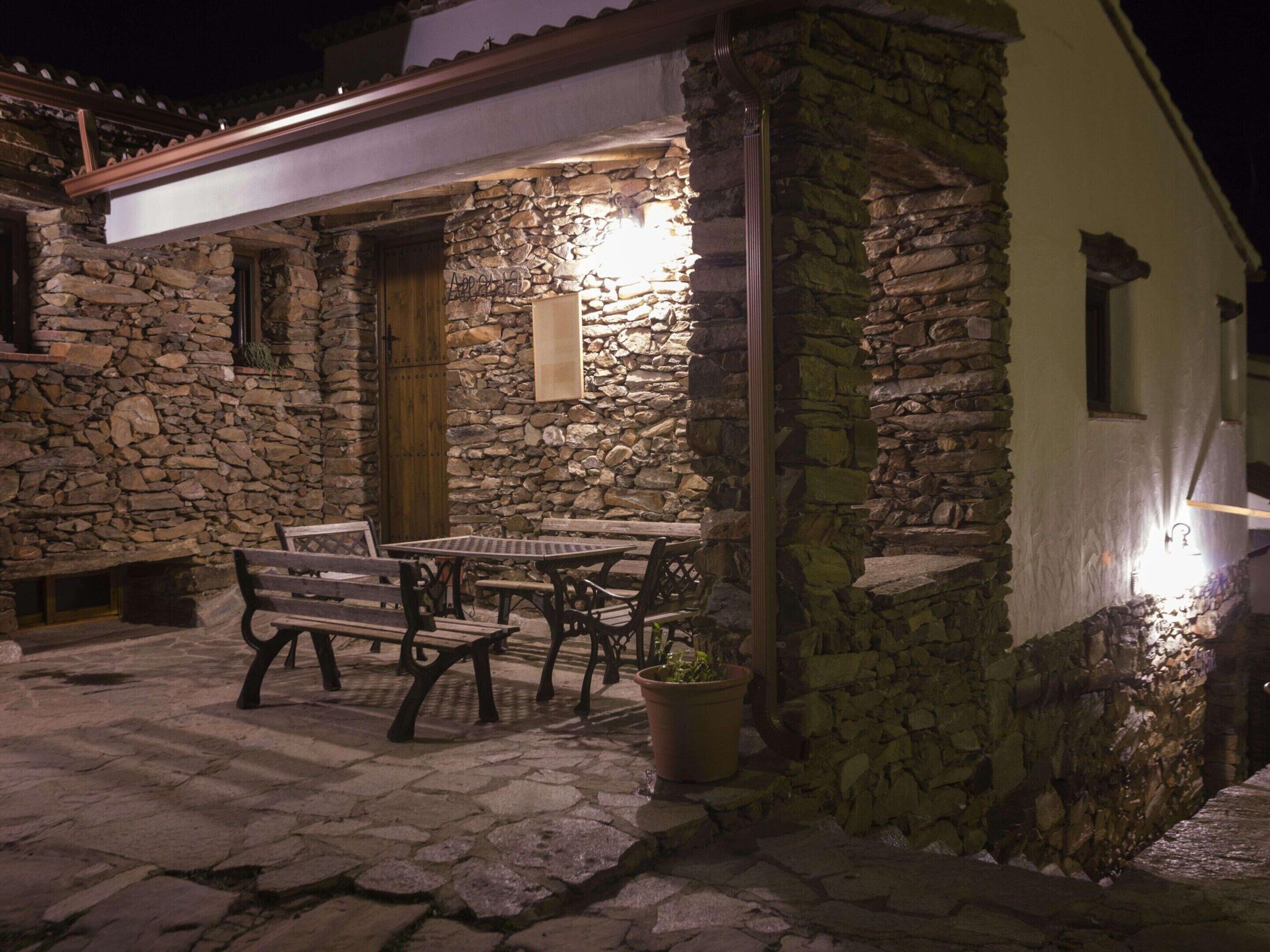 A stone building with a patio area featuring a table and benches.