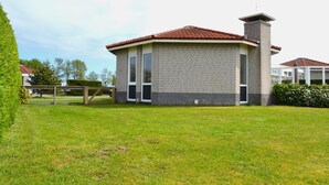 A single-story brick building with a red-tiled roof and a chimney. - Nice House on the Golf Course With Sauna (Hollum)