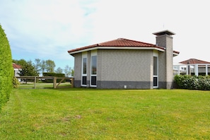 A single-story brick building with a red-tiled roof and a chimney. - Nice House on the Golf Course With Sauna (Hollum)