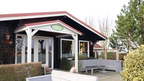 A pub with a covered outdoor seating area, a bench, and a sign that reads "A.G.'s Pub." - Nice House on the Golf Course With Sauna (Hollum)