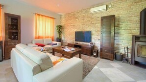 A living room with a brick wall, a sofa, a TV, and a fireplace. - Villa Tara With a Beautiful Heated Pool (Dobrinj)