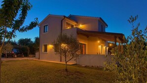 A modern two-story house with a covered porch and a small tree in the front yard. - Villa Tara With a Beautiful Heated Pool (Dobrinj)