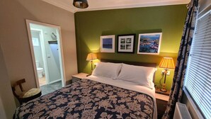 A hotel room with a bed, two bedside lamps, a radiator, and a door leading to a bathroom. - Cottage in Brookland Near Romney Marsh Beach (Romney Marsh)