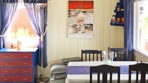 A dining area with a table set for four, chairs, a blue cabinet, and a window with curtains. - 8 Person Holiday Home in Klokkarstua (Asker)