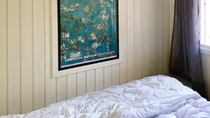 A bed with white bedding in a room with a striped wall and a framed picture of a tree. - 8 Person Holiday Home in Klokkarstua (Asker)