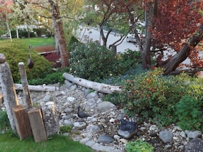 A garden with a wooden fence, rocks, and a statue of a bird. - Baldauf Modern Retreat (Riedenburg)