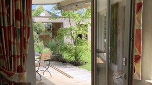 A room with a sliding glass door leading to a patio with a wooden table and chairs. - Baldauf Modern Retreat (Riedenburg)