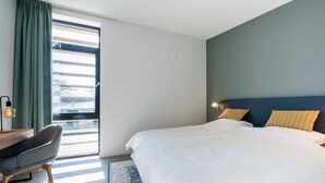 A modern bedroom with a large bed, a desk, and a chair.