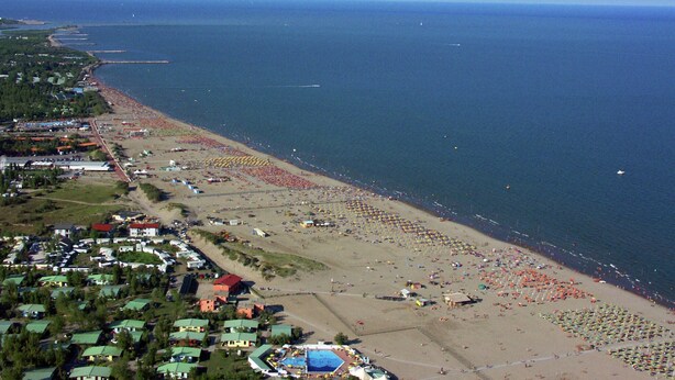 Vista aérea de uma praia com vários guarda-sóis e pessoas.