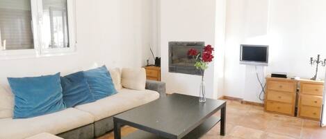 A living room with a sofa, a coffee table, a fireplace, a TV, and a TV stand.