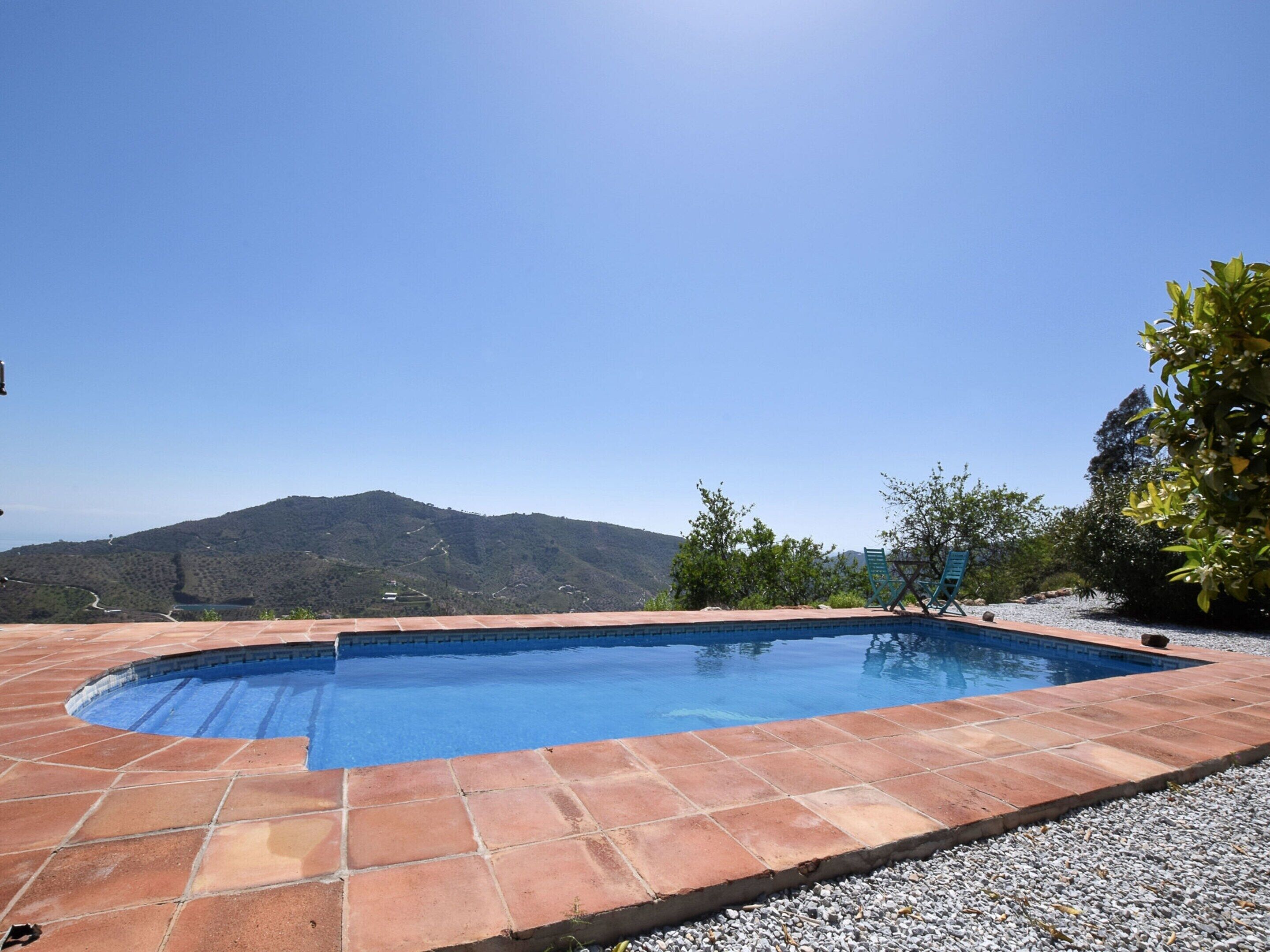 A swimming pool with a clear view of the surrounding landscape, including hills and trees.