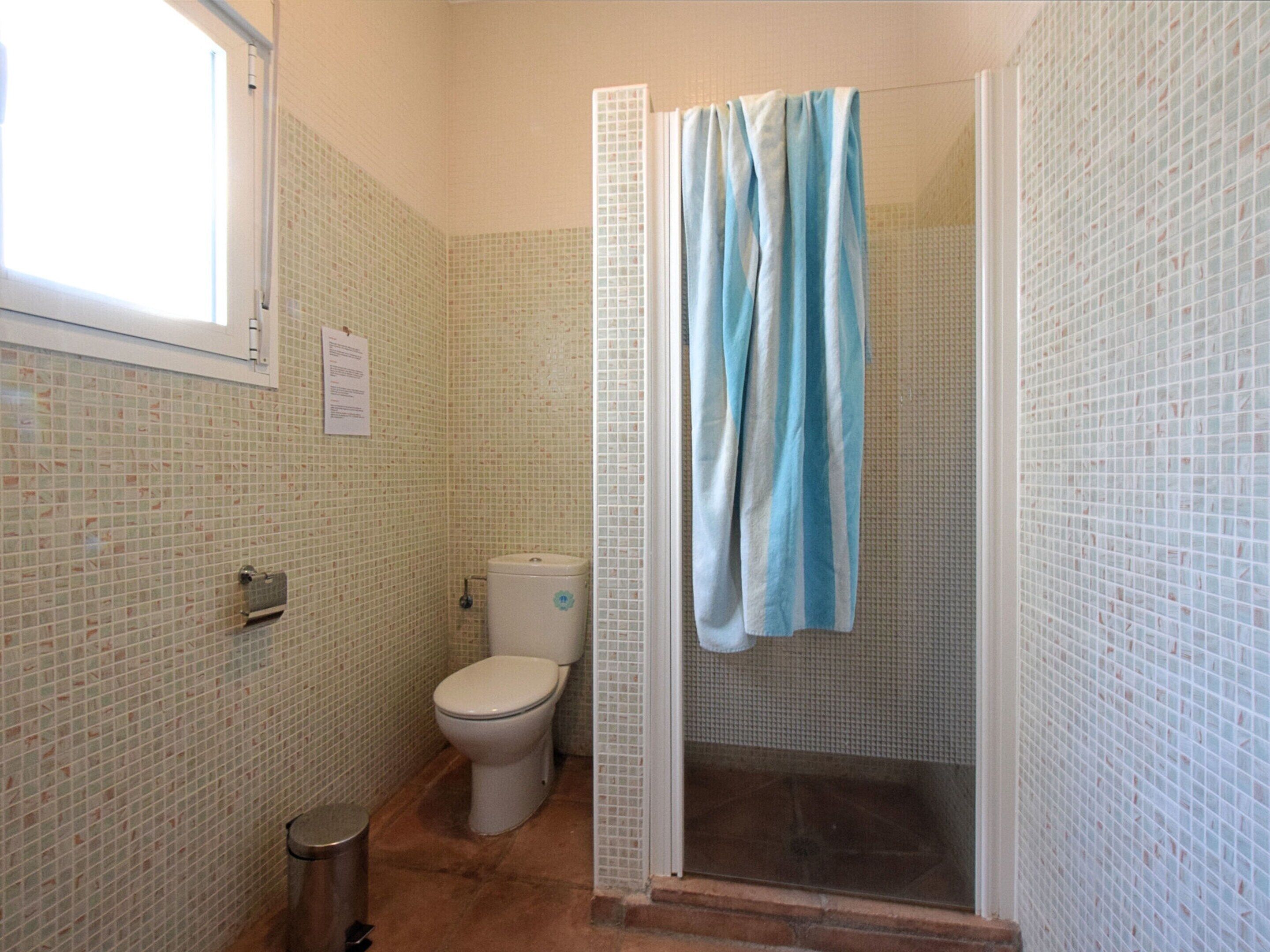 Ein Badezimmer mit Toilette, einer Dusche mit blauer Duschvorhang und gefliesten Wänden.
