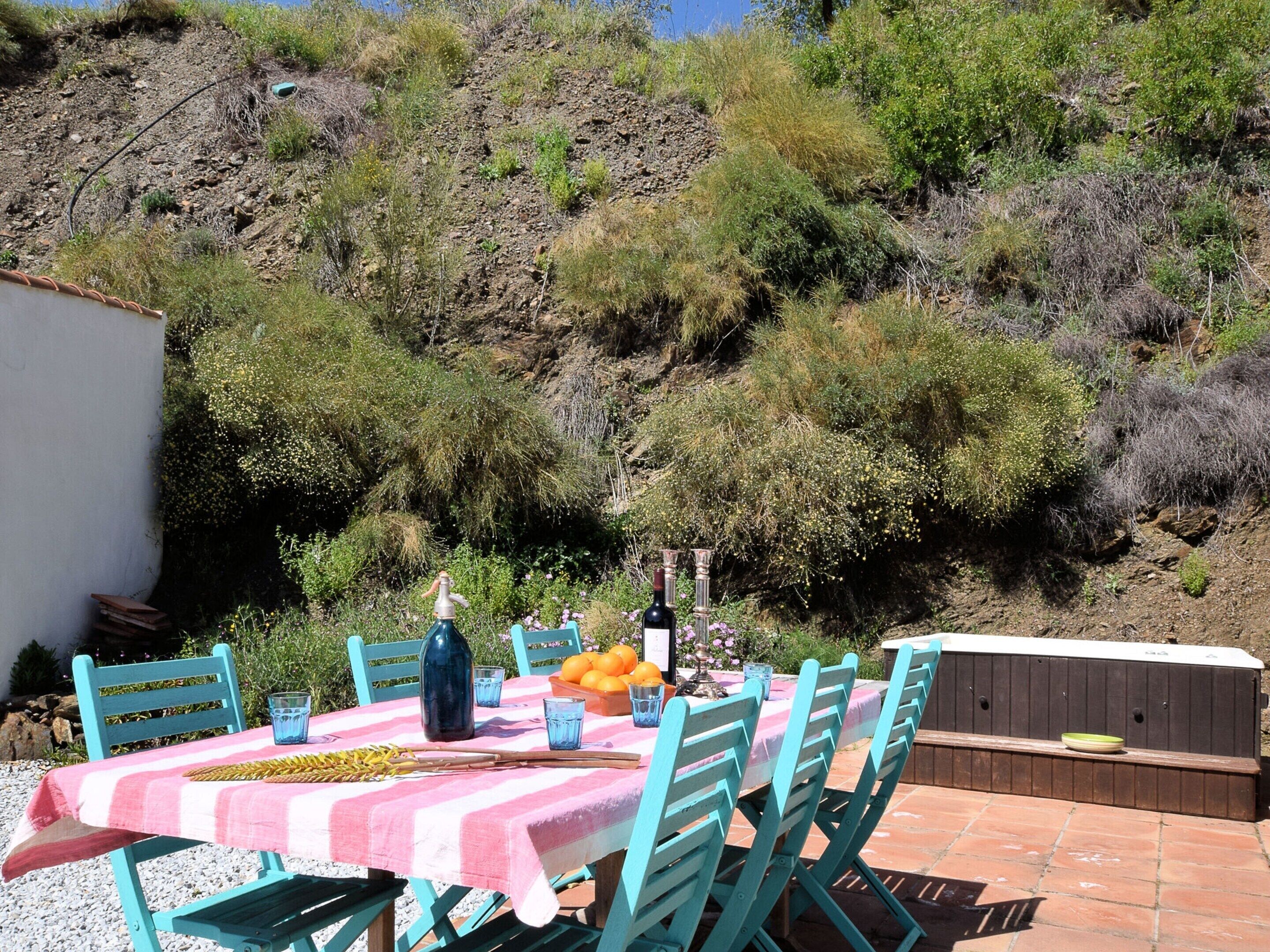 An outdoor dining area with a table set for two, surrounded by chairs, and a small kitchen area with a built-in oven.