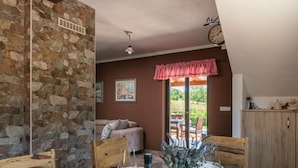 A dining area with a stone wall, wooden furniture, and a view of the outdoors. - Madonnina Comfortable Holiday Residence (Barban)