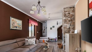 A living room with a sofa, coffee table, and a TV mounted on the wall. - Madonnina Comfortable Holiday Residence (Barban)