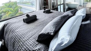 Une chambre moderne avec un grand lit, une vue sur la ville et un plafond en béton.