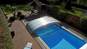Une piscine dotée d’une terrasse couverte, de chaises longues et d’un petit kiosque.