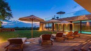 A wooden deck with outdoor furniture and umbrellas, a stone wall, and a glass-enclosed pool area. - Luxury Villa sea View (Porec)