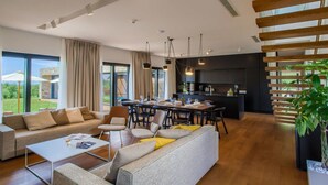 A spacious living area with a sofa set, a dining table, and a kitchen area. - Luxury Villa sea View (Porec)