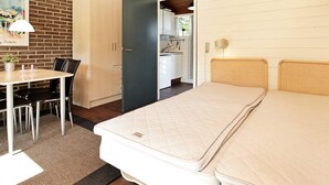 A bedroom with a bed, a desk, and a chair. There is a kitchen visible through an open door. - 2 Person Holiday Home on a Holiday Park in Aabenraa (Aabenraa)