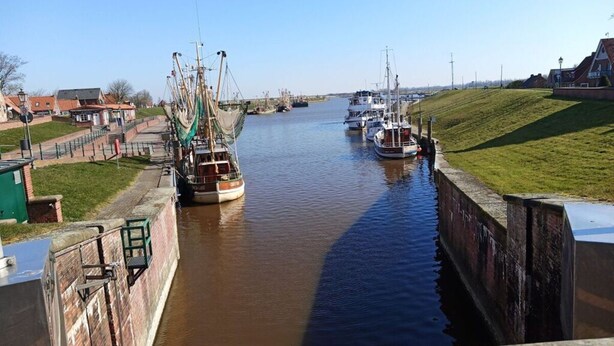 Un canal étroit où plusieurs bateaux sont amarrés de part et d’autre.