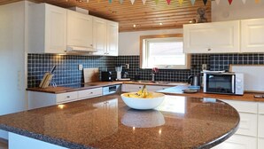 A modern kitchen with white cabinets, a granite countertop, a coffee maker, and a microwave. - 5 Star Holiday Home in Lysekil (Lysekil)