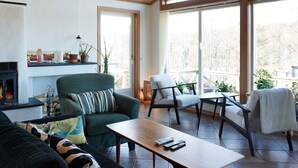 A cozy living room with a fireplace, comfortable seating, and large windows offering a view of the outdoors. - 5 Star Holiday Home in Lysekil (Lysekil)