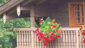 A wooden balcony with a railing, a window, and a hanging flower basket.