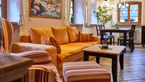 A cozy living room with a sofa, striped armchairs, a wooden coffee table, and a painting on the wall.