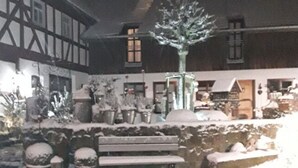 A courtyard with a snow-covered bench, a tree, and a fountain. - Stork's Nest Modern Retreat (Eichenzell)