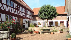 A courtyard with a cobblestone path, a bench, and potted plants. - Stork's Nest Modern Retreat (Eichenzell)
