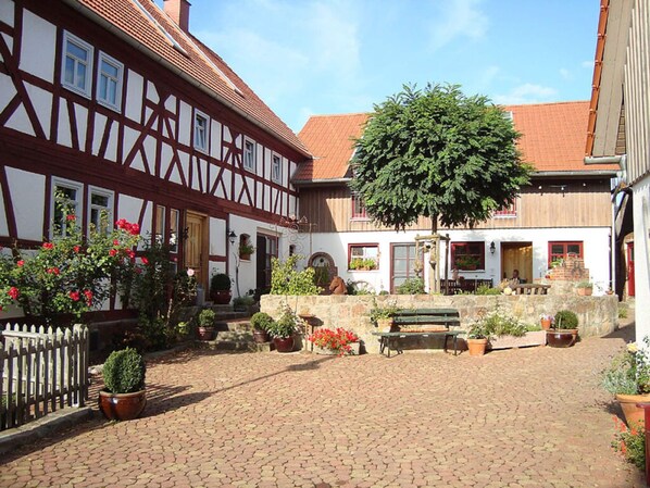 A courtyard with a cobblestone path, a bench, and potted plants.