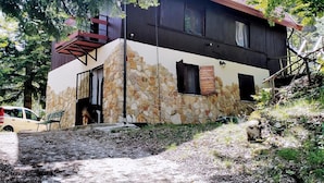 A two-story stone house with a sloped roof, wooden shutters, and a stone wall. - Belvilla by OYO La Baita (Polino)