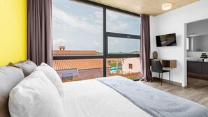 A modern hotel room with a large window, a bed, a desk, and a TV. - Belexo - Luxury Home Istria (Porec)