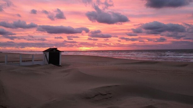 A beach with a small structure, possibly a lifeguard station, and the ocean. - Villa in St-idesbald Near Ster der Zee Beach (Koksijde)