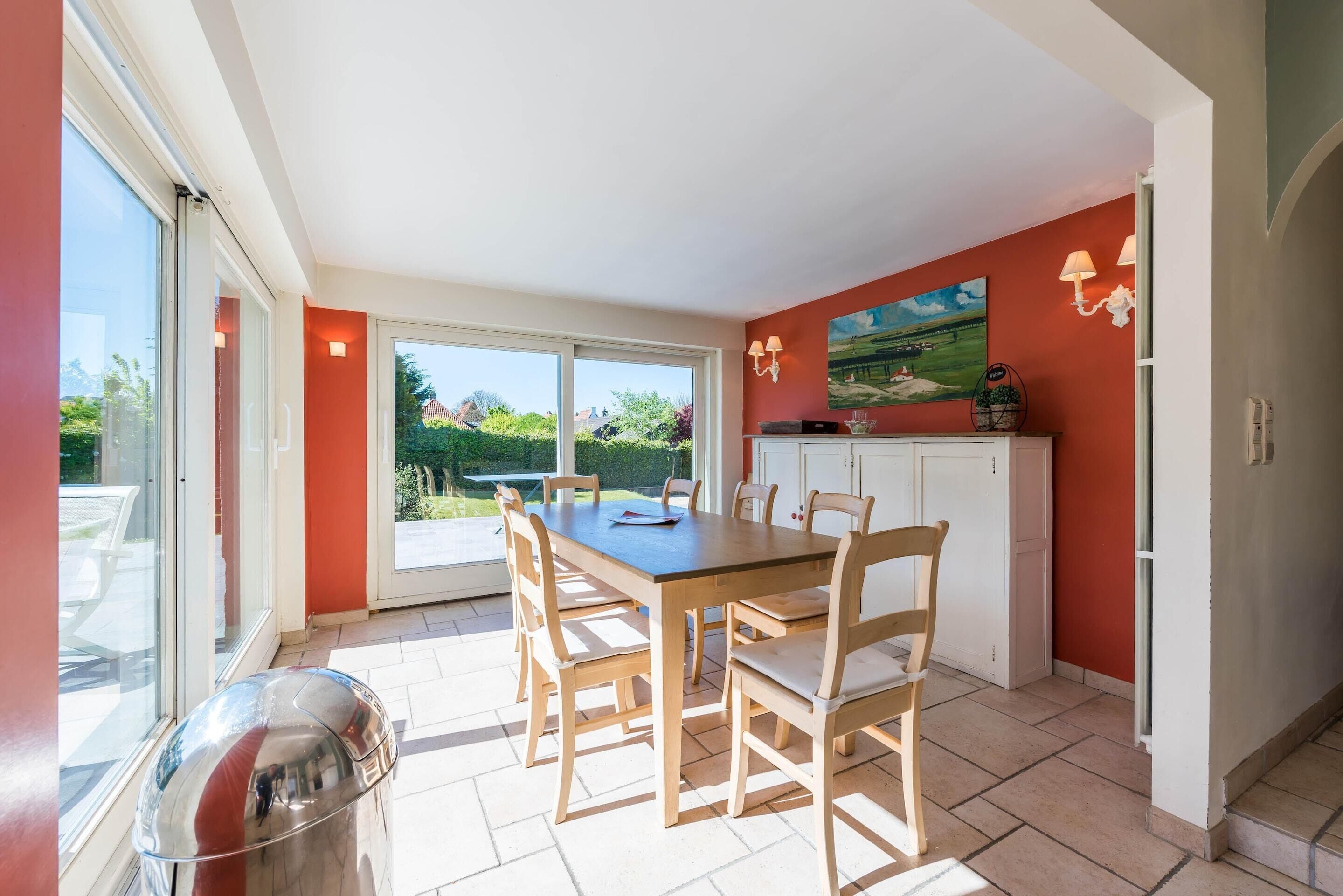 A bright kitchen with a large table and chairs, a sliding glass door leading to a patio, and a painting on the wall.
