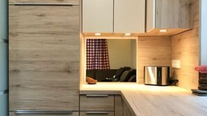 A compact kitchen with wooden cabinetry, a built-in oven, and a stainless steel refrigerator. - Alpine Hut Hannah Comfortable Vacation Home (Hermagor-Pressegger See)