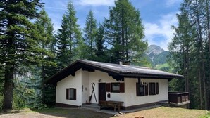 A small, single-story cabin with a sloped roof, wooden shutters, and a porch area. - Alpine Hut Hannah Comfortable Vacation Home (Hermagor-Pressegger See)