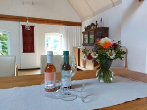 A dining table with two wine bottles, a wine glass, and a vase with flowers. - Zonnehof in het Geiseltal (Mücheln (Geiseltal))