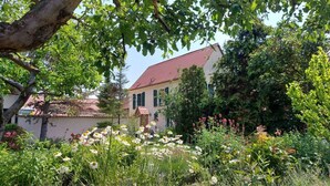 A house with a red roof, surrounded by a garden with various flowers and plants. - Zonnehof in het Geiseltal (Mücheln (Geiseltal))