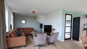 A modern living room with a sofa, two armchairs, a coffee table, and a TV. - Villa in Leons With Frisian Charm (Leons)