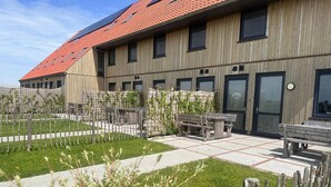 A modern building with a red-tiled roof, wooden siding, and multiple windows. - Villa in Leons With Frisian Charm (Leons)