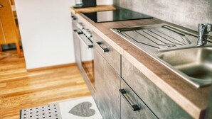 A modern kitchen with a stainless steel sink, wooden countertop, and a patterned rug on the floor. - Apartment in Hohentauern With Sauna (Hohentauern)