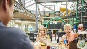 A group of people dining at an outdoor restaurant with a high ceiling and a view of a playground in the background. - Beautiful Holiday Home With Luxury Bbq, in Limburg (Roggel)