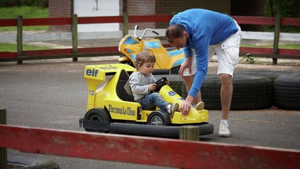 A child in a yellow go-kart with "elf" and "Formula Uno" branding, being assisted by an adult. - Beautiful Holiday Home With Luxury Bbq, in Limburg (Roggel)