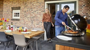 An outdoor dining area with a brick wall, wooden beams, and a grill station. - Beautiful Holiday Home With Luxury Bbq, in Limburg (Roggel)